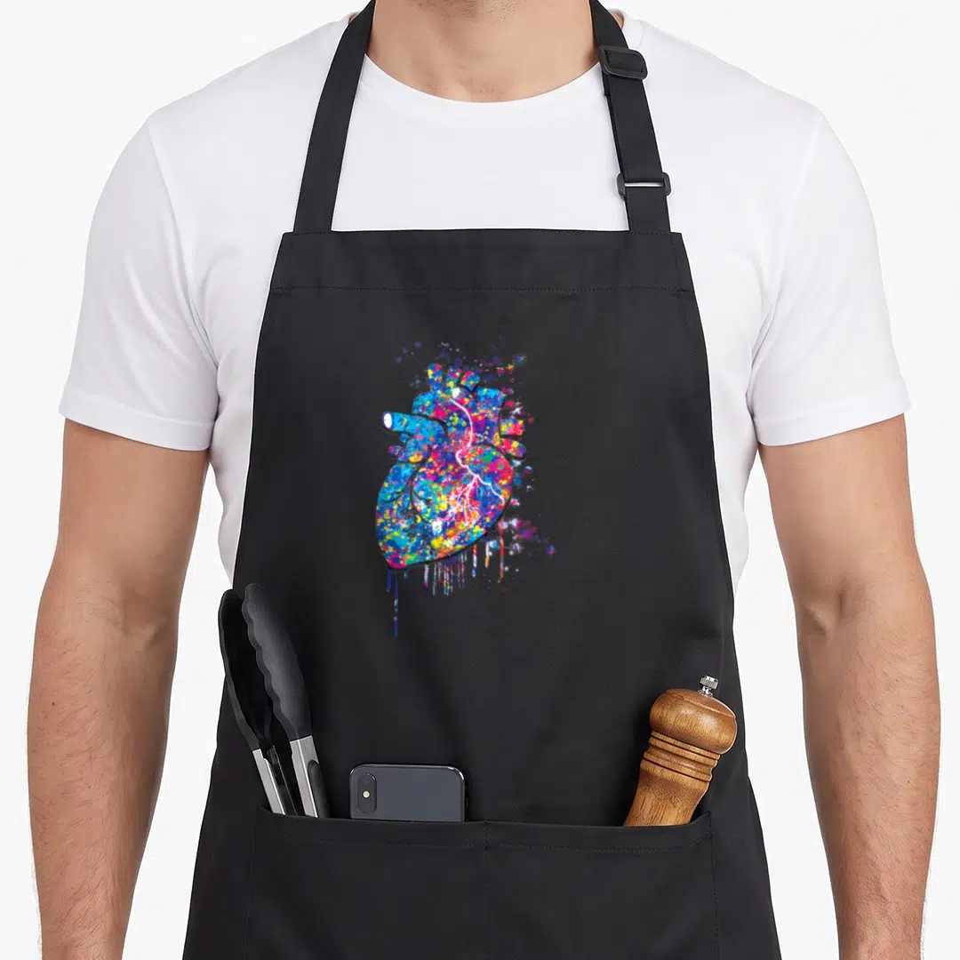 Hitta workout motivation apron - Anatomical heart in multicolored paint splatter with blue red yellow pink purple drips — shown on a black cotton canvas apron against a white background