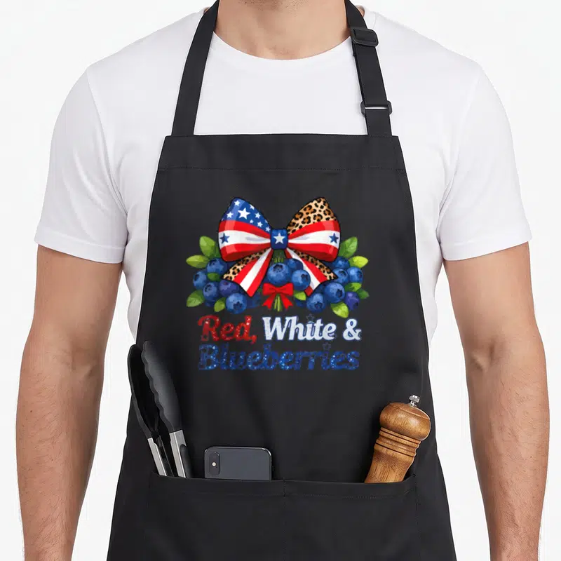 Blueberry patriotic apron - Bow with stars stripes and leopard print over blueberries with text Red White — shown on a black cotton canvas apron against a white background