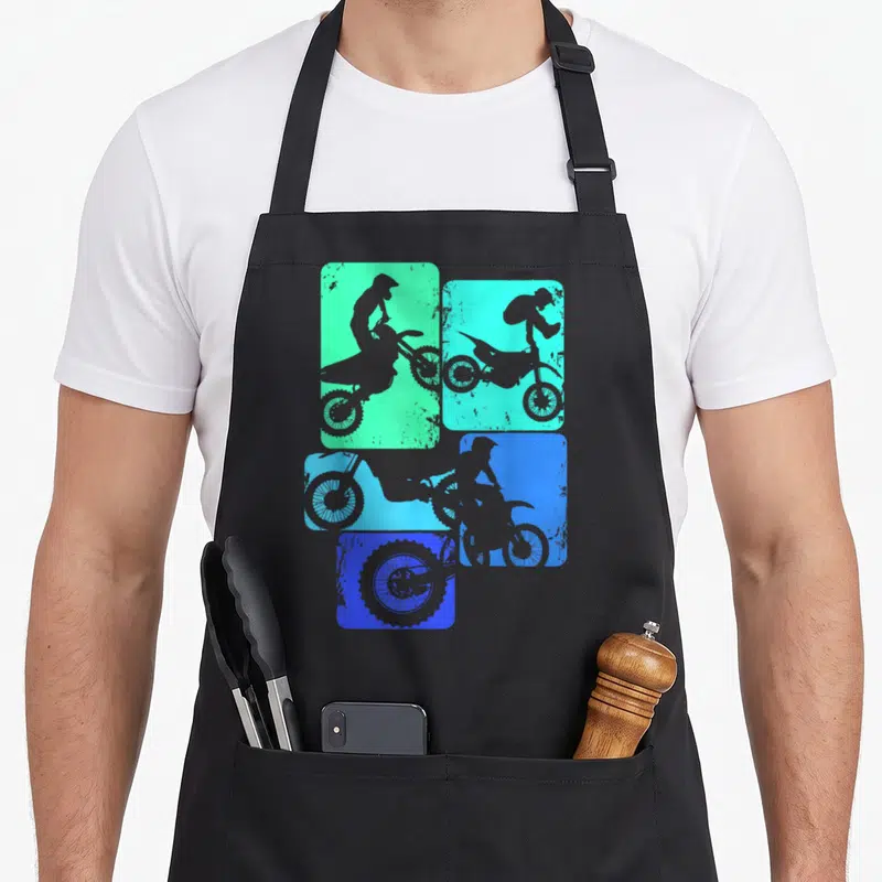 Rider motocross bike apron - Four grey motocross rider silhouettes on green, cyan, and blue distressed gradient panels — shown on a black cotton canvas apron against a white background