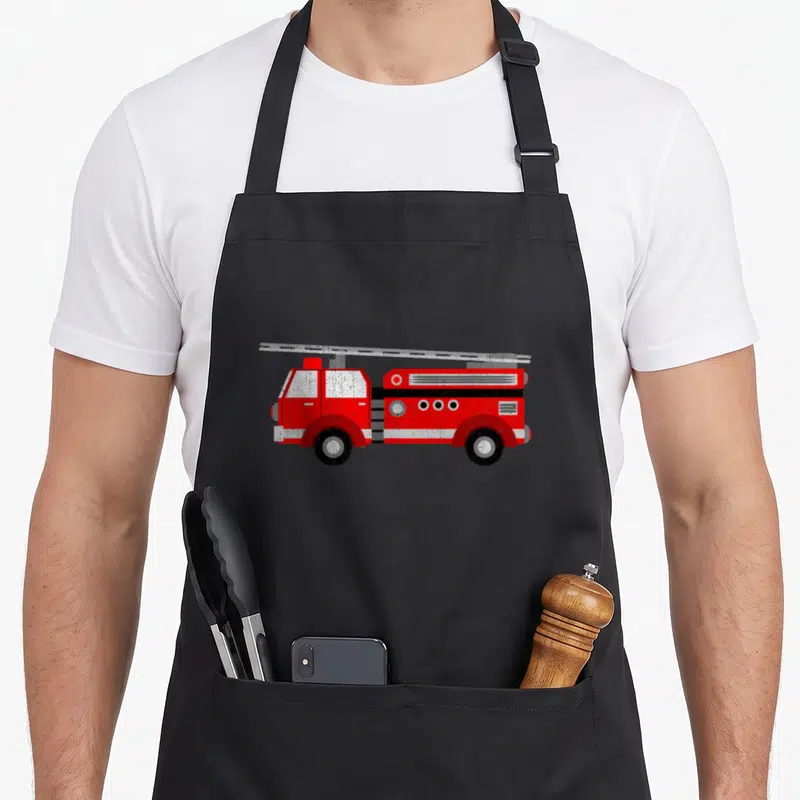 Fire trailer apron - Red fire truck with ladder and black wheels in cartoon style — shown on a black cotton canvas apron against a white background