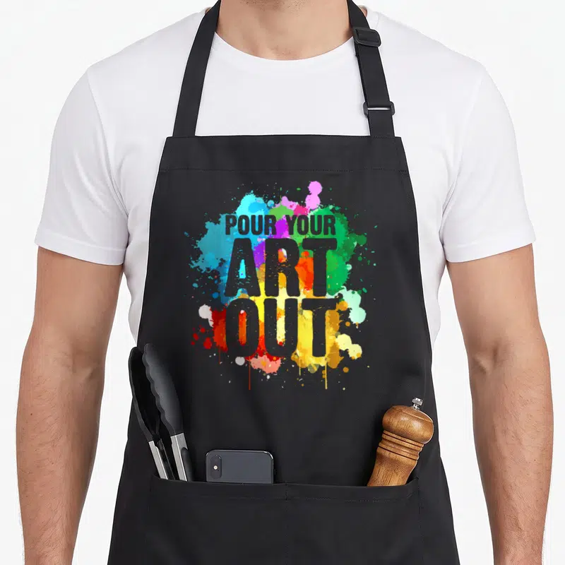 Artist paint painter apron - Grey text POUR YOUR ART OUT over blue, purple, green, yellow, red, and grey watercolor — shown on a black cotton canvas apron against a white background
