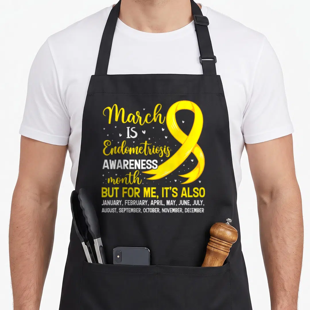 March endometriosis awareness apron - Yellow ribbon and text listing all months of the year for endometriosis support — shown on a black cotton canvas apron against a white background