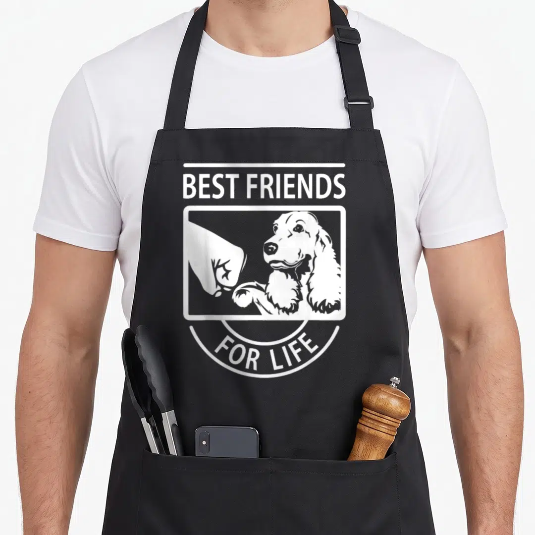 Friend cocker spaniel apron - White line art of dog fist bumping human hand with BEST FRIENDS FOR LIFE text — shown on a black cotton canvas apron against a white background