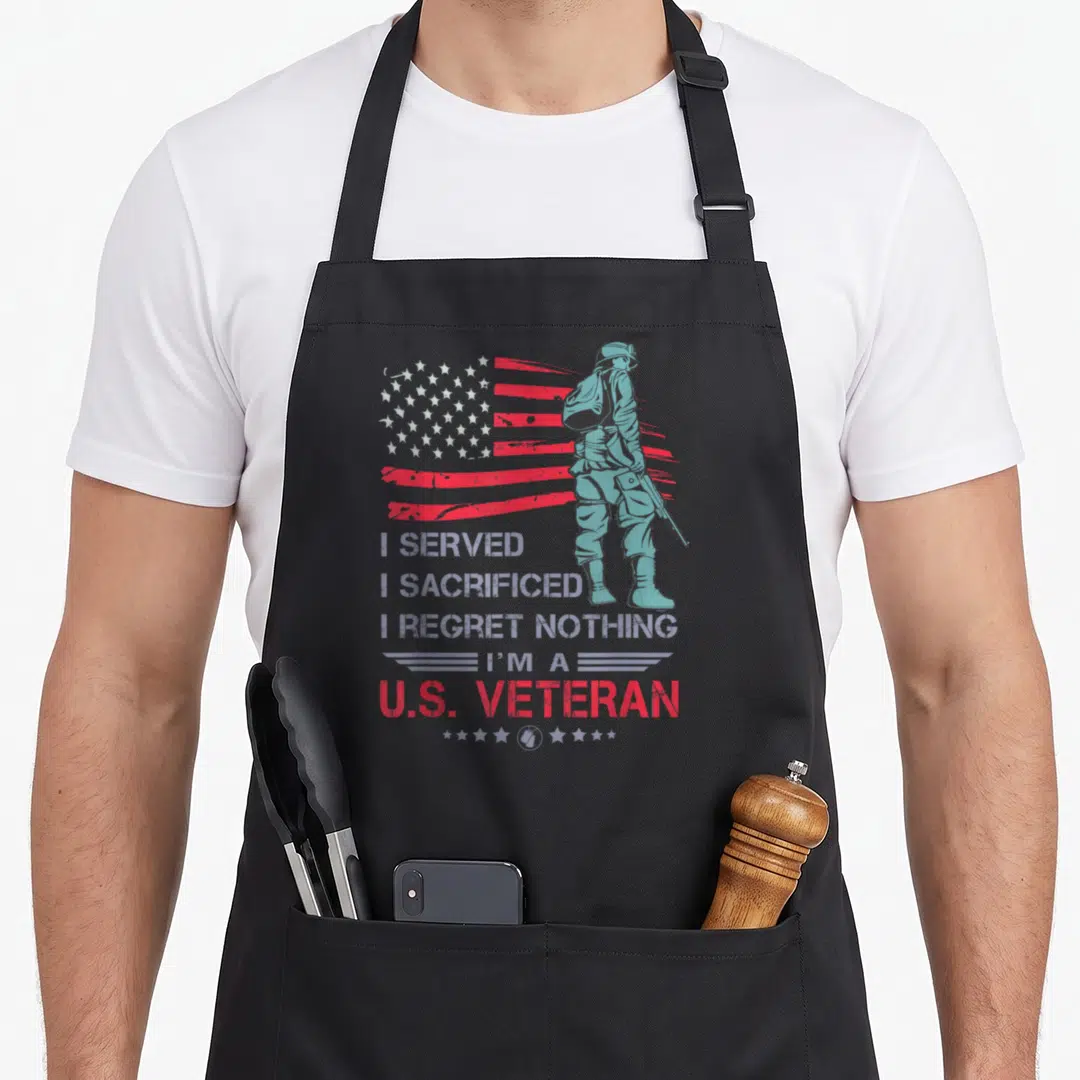 Served veterans day apron - Soldier silhouette before distressed red white flag with stacked text I served I sacrificed — shown on a black cotton canvas apron against a white background