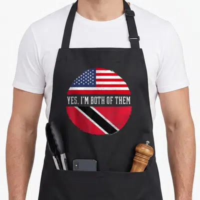 Trinidad american flag apron - Distressed circular design with US and Trinidad flags and text Yes Im Both Of Them — shown on a black cotton canvas apron against a white background