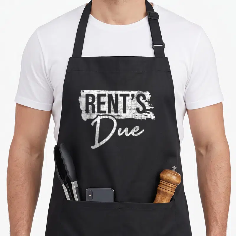 Rent every second apron - White distressed typography reading RENT'S Due stacked vertically — shown on a black cotton canvas apron against a white background