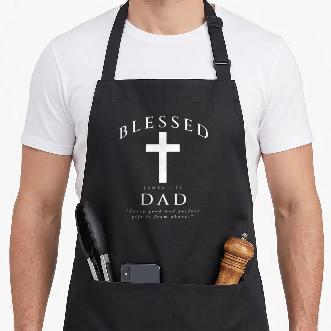 Jame christian apron - White cross and BLESSED DAD typography with James 1:17 quote on black fabric — shown on a black cotton canvas apron against a white background