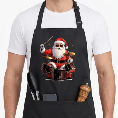 Drummer santa claus apron - Cartoon Santa Claus in red suit and sunglasses playing black drum kit with gold cymbals — shown on a black cotton canvas apron against a white background