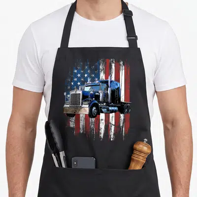 Driver american flag apron - Realistic semi-truck over distressed blue red white and silver USA flag — shown on a black cotton canvas apron against a white background