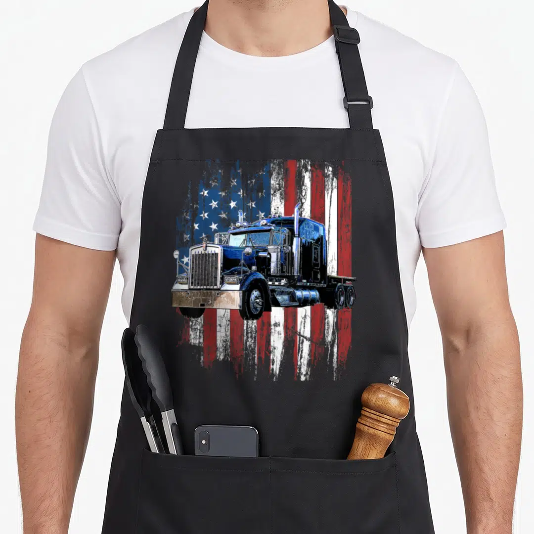Driver american flag apron - Realistic semi-truck over distressed blue red white and silver USA flag — shown on a black cotton canvas apron against a white background