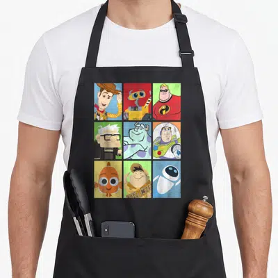 Collection character aprons - WALL-E and nine Pixar character portraits in a colorful 3x3 grid layout — shown on a black cotton canvas apron against a white background