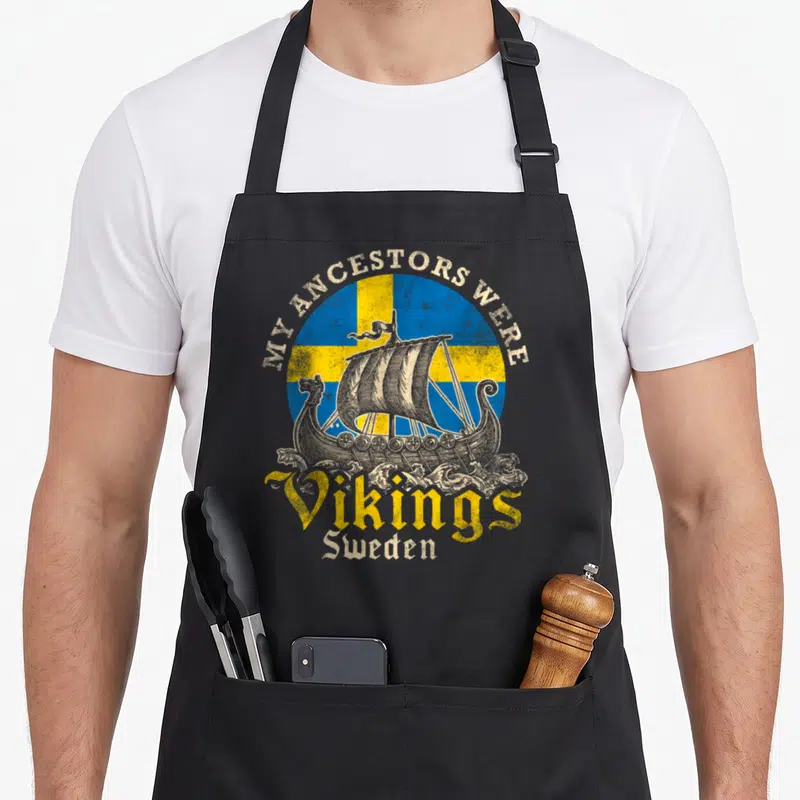 Sweden swedish apron - Retro viking ship on blue yellow flag with My Ancestors Were Vikings Sweden text — shown on a black cotton canvas apron against a white background
