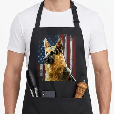 Patriotic dog mom apron - Realistic German Shepherd head over distressed American flag in tan and patriotic colors — shown on a black cotton canvas apron against a white background