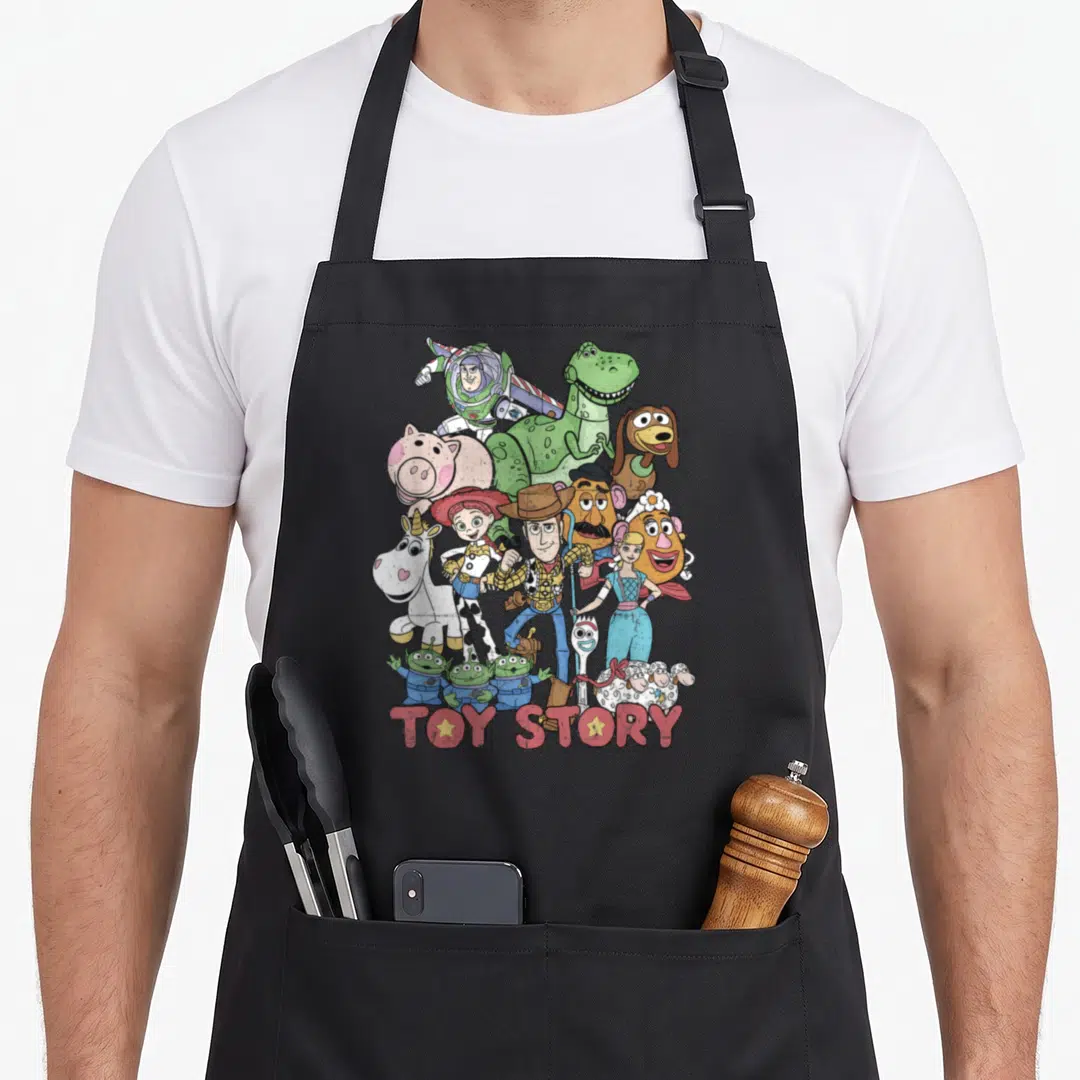 Star camping apron - Toy Story cartoon characters piled together with red logo text at bottom — shown on a black cotton canvas apron against a white background