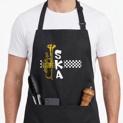 Ska square apron - Yellow trumpet beside vertical white SKA text and white checkerboard strip — shown on a black cotton canvas apron against a white background