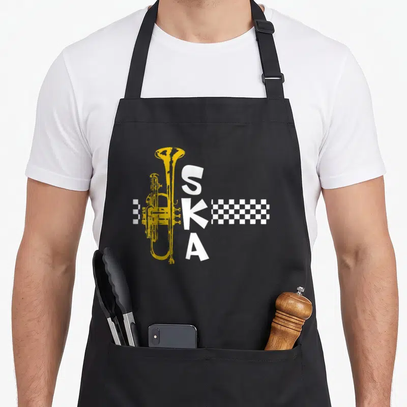 Ska square apron - Yellow trumpet beside vertical white SKA text and white checkerboard strip — shown on a black cotton canvas apron against a white background