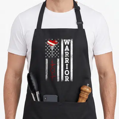 Surgery warrior open apron - Zipper opening red heart over stars with vertical WARRIOR text and red heartbeat line — shown on a black cotton canvas apron against a white background