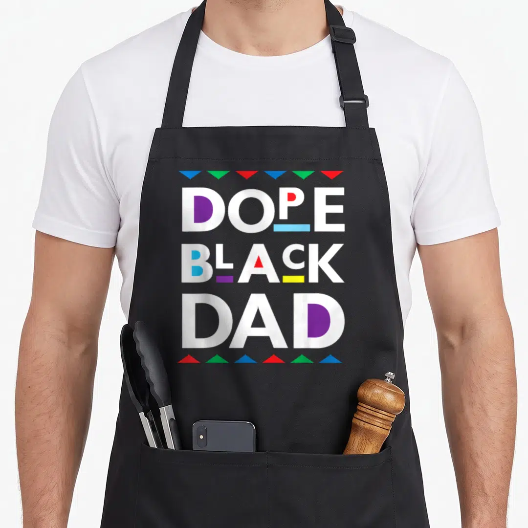 History black dad apron - Stacked DOPE BLACK DAD text with purple blue red yellow green accents and triangle borders — shown on a black cotton canvas apron against a white background
