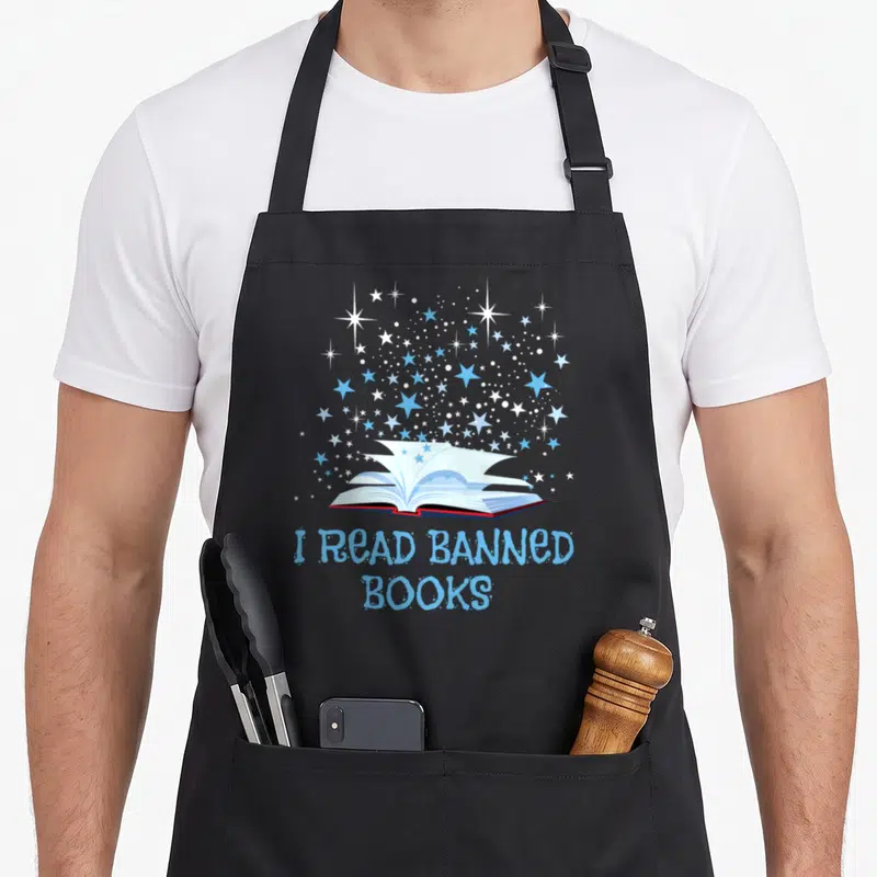 Read banned nerd apron - Open book with blue and white stars and text I READ BANNED BOOKS — shown on a black cotton canvas apron against a white background