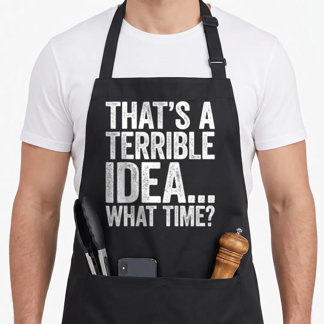 Terrible flask apron - White distressed stacked text reading That's A Terrible Idea What Time on black bib — shown on a black cotton canvas apron against a white background