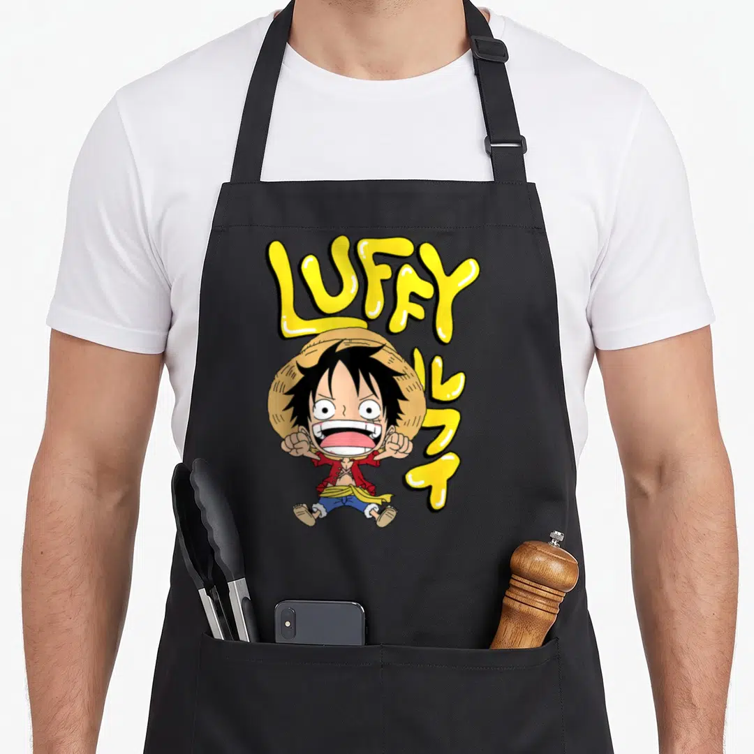 Letter anime apron - Chibi Luffy character with yellow LUFFY bubble letters and vertical Japanese katakana text — shown on a black cotton canvas apron against a white background