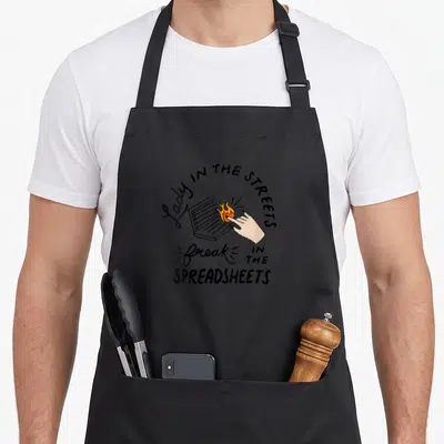 Street up addict apron - Cartoon hand touching laptop causing orange fire with text Lady IN THE STREETS and freak — shown on a black cotton canvas apron against a white background