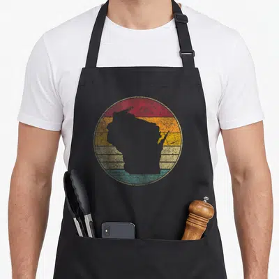 Distressed wisconsin apron - Grey Wisconsin silhouette on retro circle with red orange yellow beige and teal stripes — shown on a black cotton canvas apron against a white background