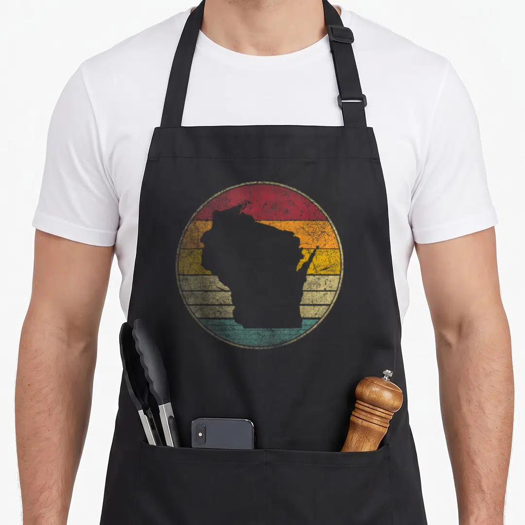 Distressed wisconsin apron - Grey Wisconsin silhouette on retro circle with red orange yellow beige and teal stripes — shown on a black cotton canvas apron against a white background