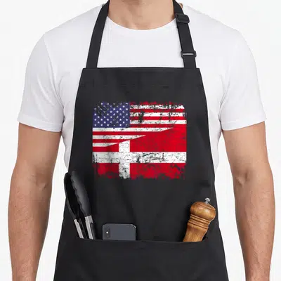 Danish american flag apron - Distressed merged US and Danish flags in red white blue diagonal layout — shown on a black cotton canvas apron against a white background