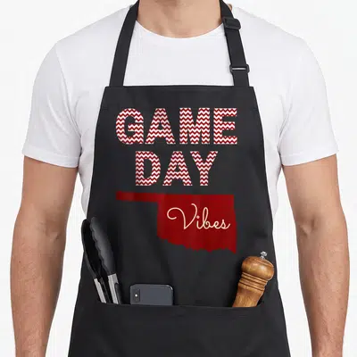 Oklahoma fall apron - Red white chevron GAME DAY text above Oklahoma silhouette with Vibes script — shown on a black cotton canvas apron against a white background