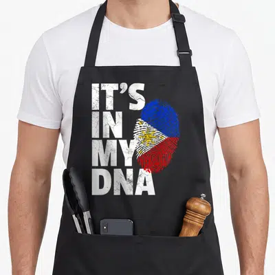 Dna filipino pride apron - Distressed IT'S IN MY DNA text next to a Philippine flag fingerprint in blue red and yellow — shown on a black cotton canvas apron against a white background
