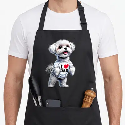 Maltese love dog apron - Realistic white fluffy dog wearing a shirt printed with I ❤️ DAD and a red heart symbol — shown on a black cotton canvas apron against a white background