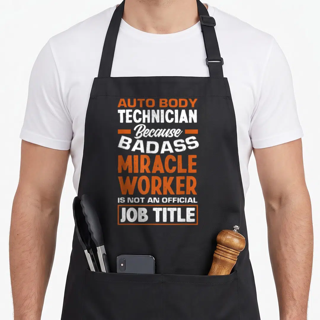 Miracle badass apron - Orange and white typography reading Auto Body Technician Because Badass Miracle Worker Is Not — shown on a black cotton canvas apron against a white background