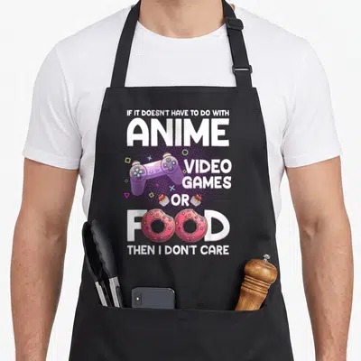 Retro anime apron - Purple game controller, pink donuts forming text, and stacked white lettering on dotted background — shown on a black cotton canvas apron against a white background