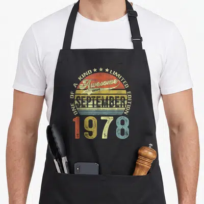 43th birthday apron - Retro striped sun with text Awesome since September 1978 Limited Edition One of a Kind — shown on a black cotton canvas apron against a white background