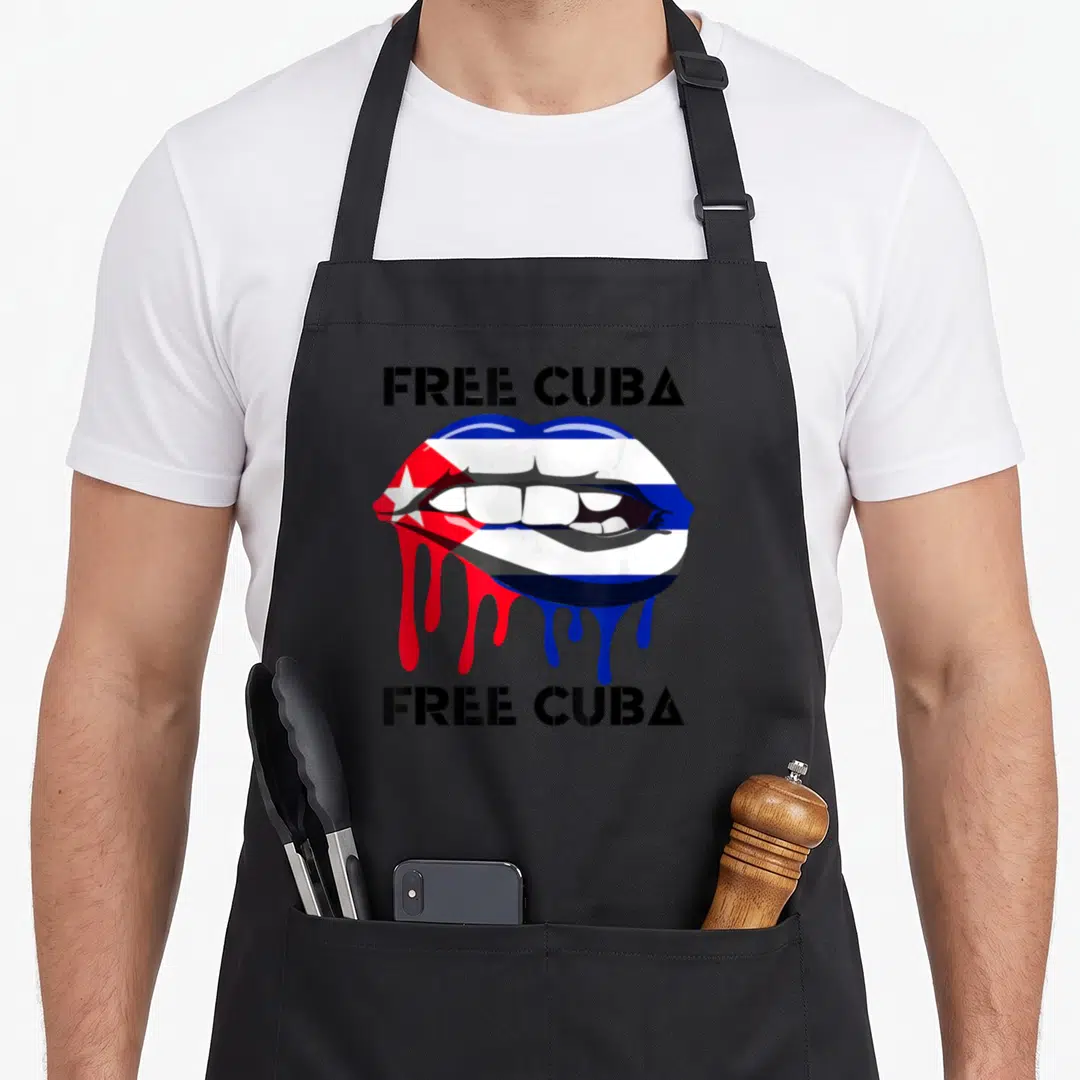 Vida pride apron - Free Cuba text above and below cartoon lips with dripping flag pattern — shown on a black cotton canvas apron against a white background