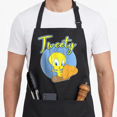 Tweety bird apron - Yellow cartoon bird on a swing in a blue circle with arched Tweety text — shown on a black cotton canvas apron against a white background