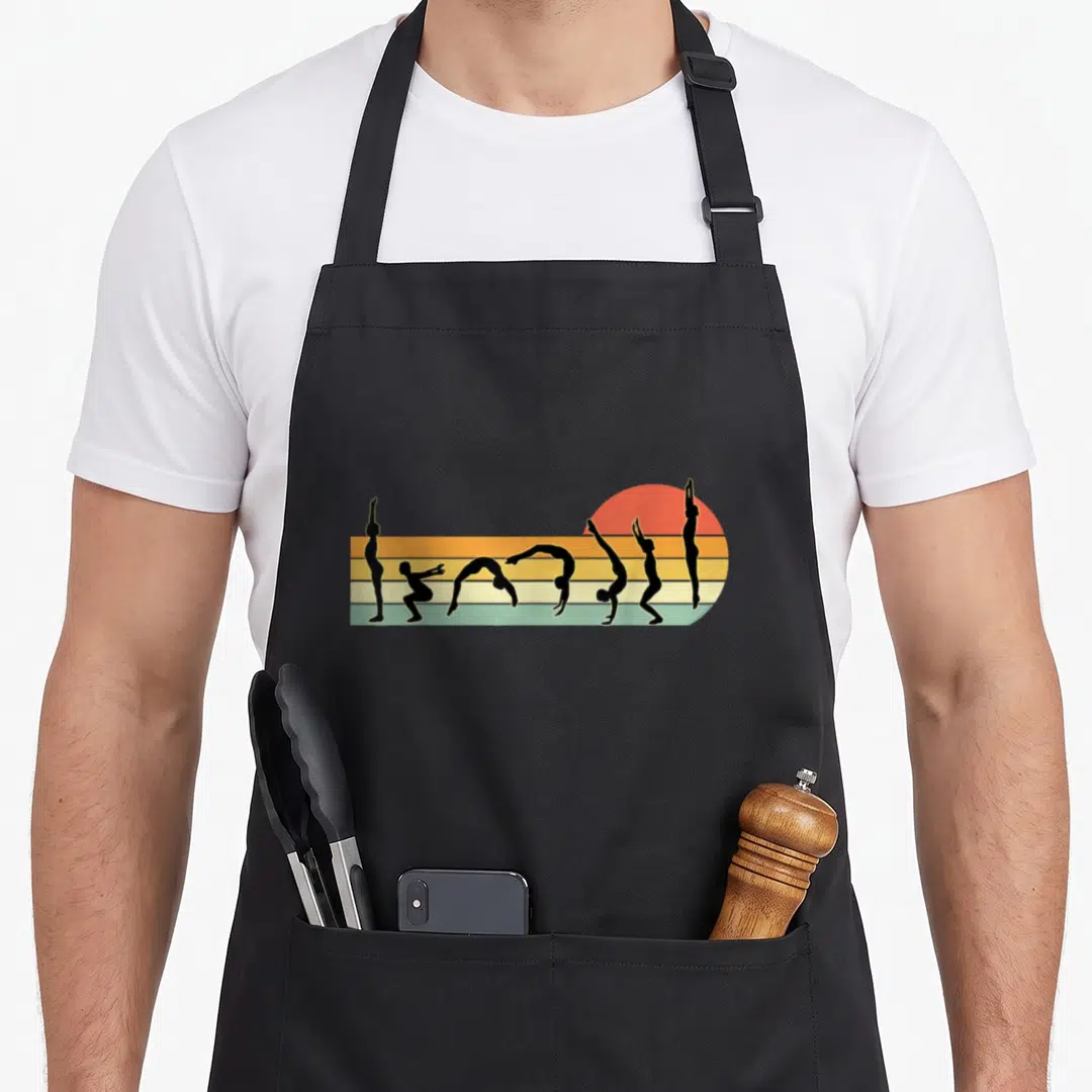 Sunset gymnastics apron - Seven black gymnast silhouettes in poses over horizontal stripes and red sun — shown on a black cotton canvas apron against a white background