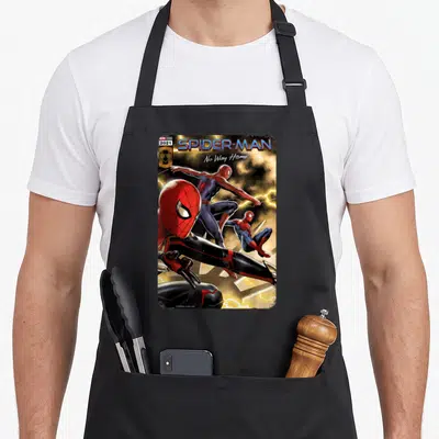 Spider cover apron - Three Spider-Man suits against yellow lightning with MARVEL STUDIOS 2021 text — shown on a black cotton canvas apron against a white background