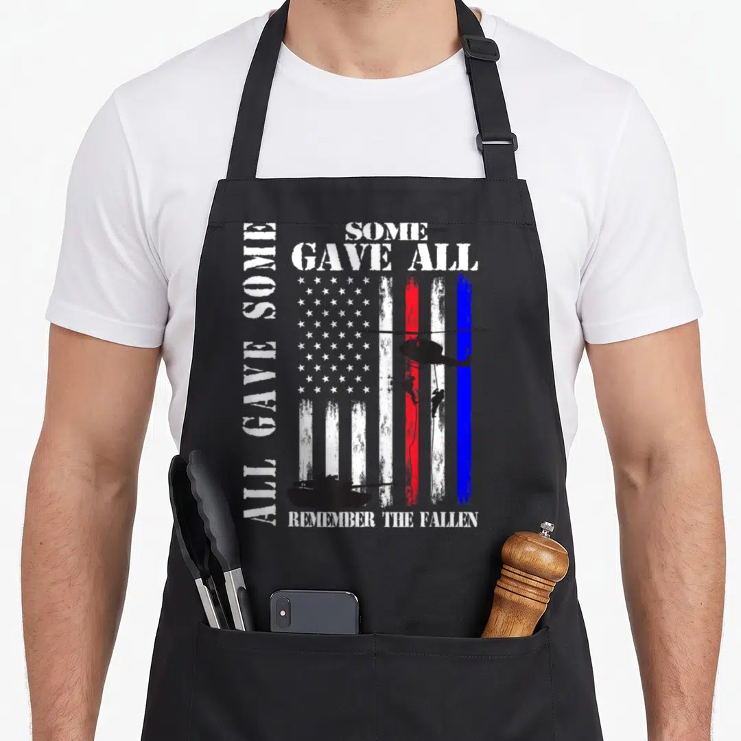 Gave family aprons - Distressed USA flag with helicopter soldiers tank and All Gave Some Some Gave All Remember — shown on a black cotton canvas apron against a white background