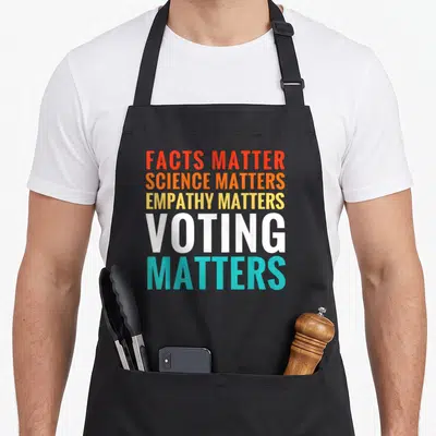 Fact science apron - Stacked colorful text Facts Matter Science Matters Empathy Matters Voting Matters typography — shown on a black cotton canvas apron against a white background