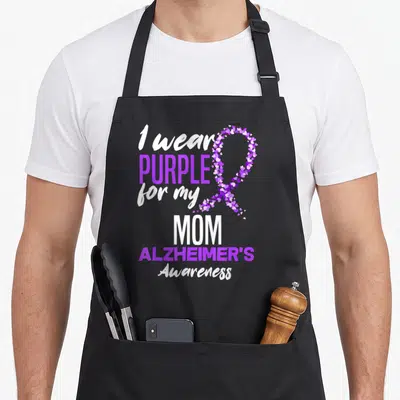 Dementia alzheimer's aprons - I wear PURPLE for my MOM ALZHEIMER'S Awareness text with heart ribbon — shown on a black cotton canvas apron against a white background