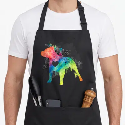 Pitbull lover comfort apron - Rainbow watercolor pitbull silhouette with grey heart, swirls, butterflies, and PITBULL — shown on a black cotton canvas apron against a white background
