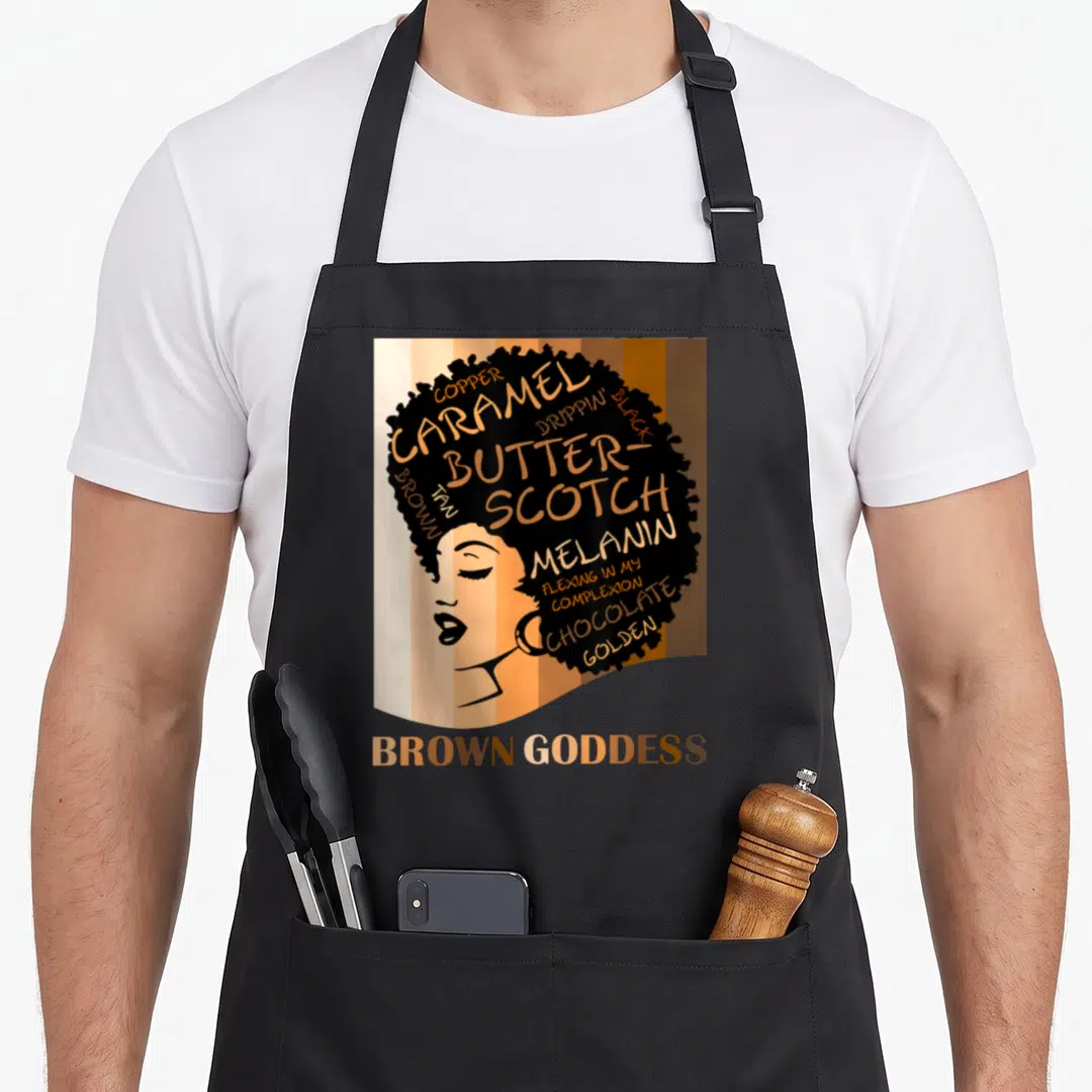 Goddess beautiful apron - Woman profile with afro filled with skin tone words and Brown Goddess text below — shown on a black cotton canvas apron against a white background