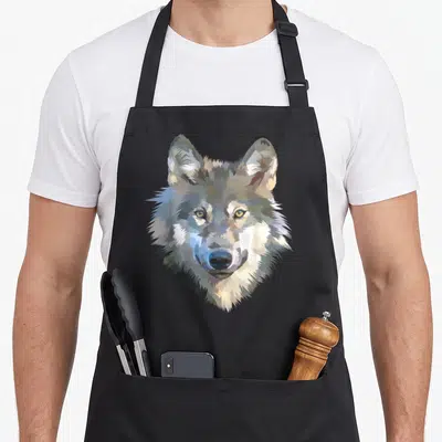 Realistic animal print apron - Pixel art wolf head in grey white and brown centered on apron front — shown on a black cotton canvas apron against a white background