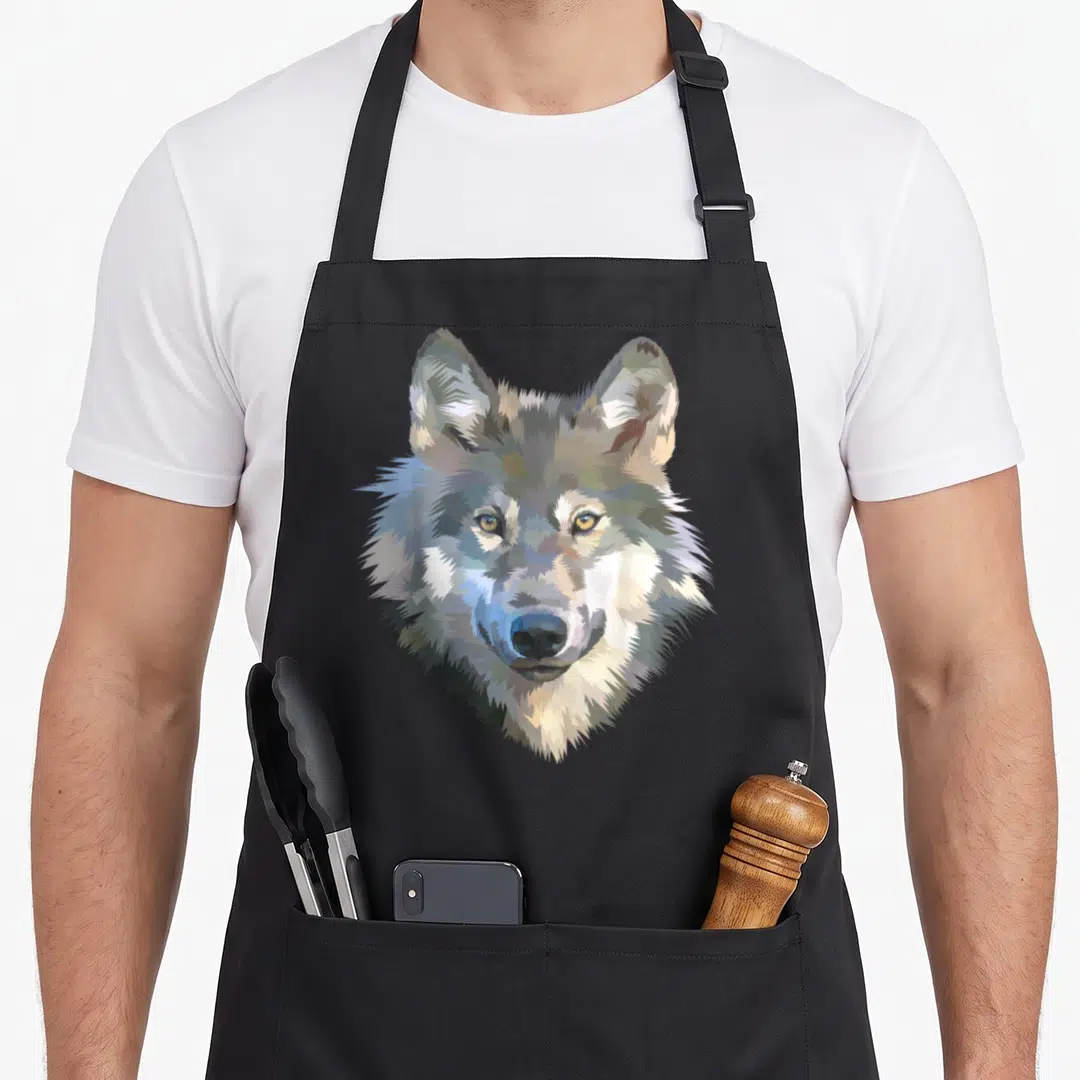 Realistic animal print apron - Pixel art wolf head in grey white and brown centered on apron front — shown on a black cotton canvas apron against a white background