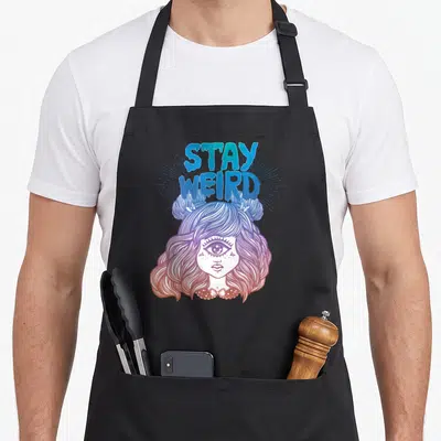 Alien weird aprons - STAY WEIRD text above girl with third eye in blue purple pink orange line art — shown on a black cotton canvas apron against a white background
