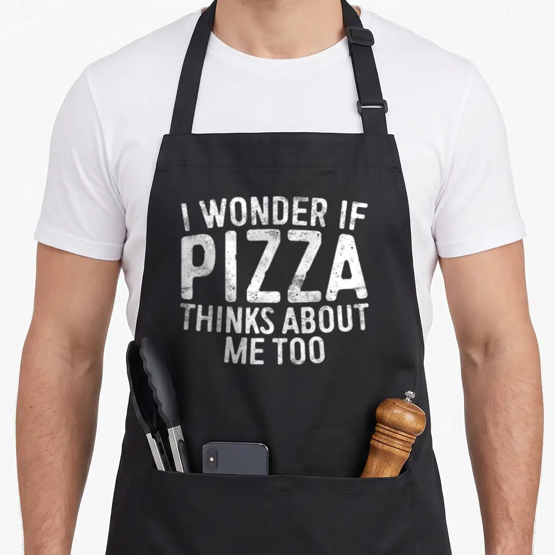 Wonder pizza apron - White distressed text reading I WONDER IF PIZZA THINKS ABOUT ME TOO stacked vertically — shown on a black cotton canvas apron against a white background