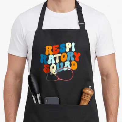 Respiratory graphic squad apron - Retro multicolored RESPI RATORY SQUAD text with red stethoscope — shown on a black cotton canvas apron against a white background