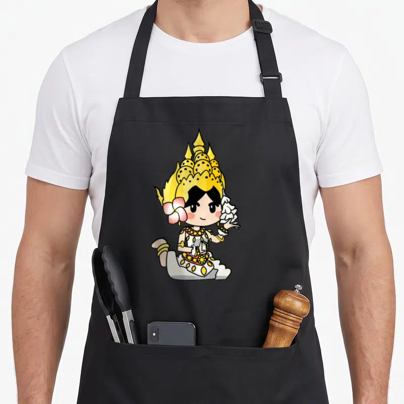 Adorable beauty apron - Chibi Thai dancer in gold crown and white robe with pink flower accent — shown on a black cotton canvas apron against a white background